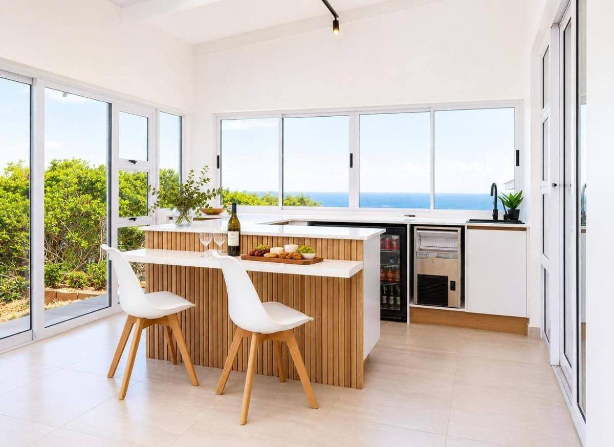 Indoor bar with ocean views through sliding doors at ONPOINT27 Pinnacle Point Lodge